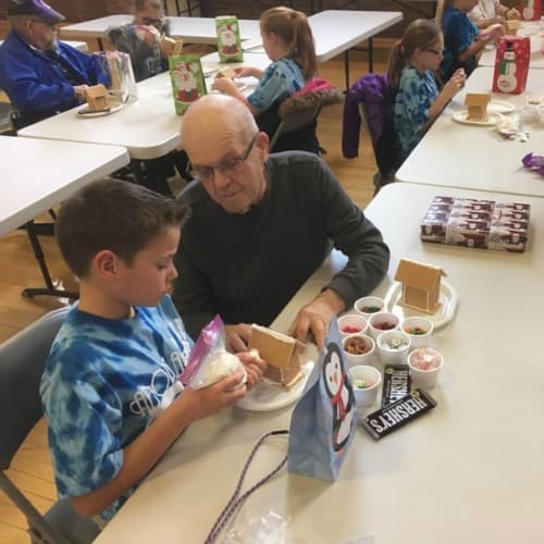 Young child with a grandparent decorating gingerbread houses