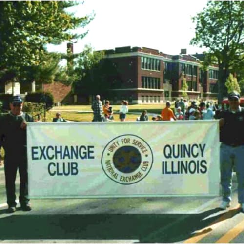 Exchange Club sign being held by two men at a parade